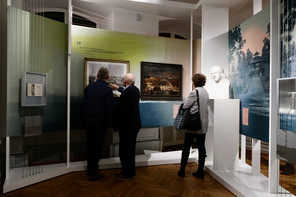 Drei Besucher stehen in einem Ausstellungsraum vor Exponaten